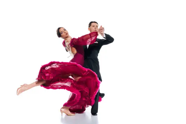 Photo of elegant young couple of ballroom dancers in red dress in suit dancing on white