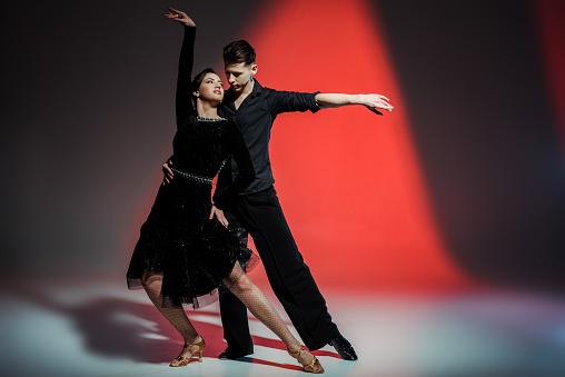 elegant young couple of ballroom dancers dancing in red light