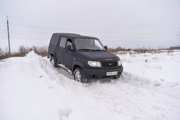 Russian black 4x4 SUV in protective paint Raptor "UAZ Patriot Pickup" quickly moves off a snow Bank in the winter. Russia, Novosibirsk-March 5, 2020. Russian black 4x4 SUV in protective paint Raptor "UAZ Patriot Pickup" quickly moves off a snow Bank in the winter. uaz 4x4 land vehicle woods stock pictures, royalty-free photos & images