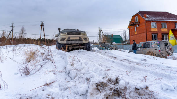Russian white SUV "UAZ Patriot" with its nose raised high drives into a snowdrift. Russia, Novosibirsk-March 5, 2020. Russian white SUV "UAZ Patriot" with its nose raised high drives into a snowdrift. uaz 4x4 land vehicle woods stock pictures, royalty-free photos & images