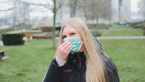istock Young female feeling saved by putting on face medical mask 1214521684