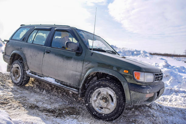 オフロードsuv「日産テラノ4x4」は、ターンで冬に雪道に乗ってブリザードのスプレーですぐに。 - off road vehicle 4x4 jeep mud ストックフォトと画像