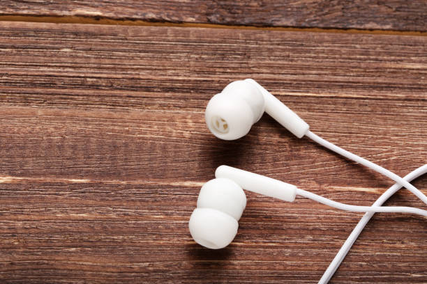 istock White earphones on brown wooden table 1214522525