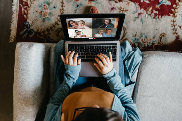 giovane donna che usa un laptop per connettersi con i suoi amici e genitori durante la quarantena - social distancing foto e immagini stock