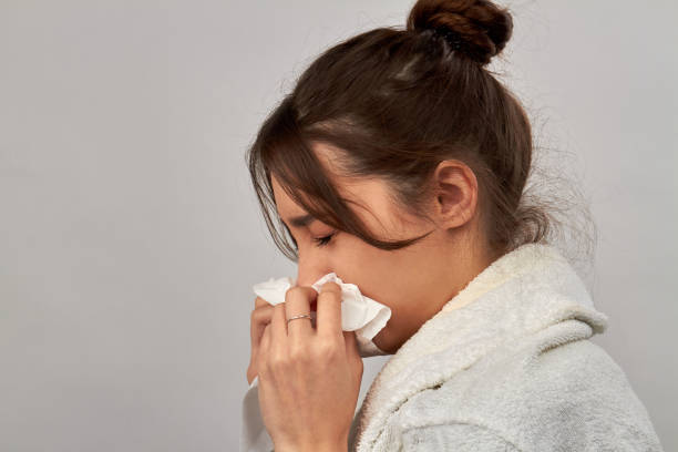 istock Side view young woman blowing nose in disposable napkin. 1214524411