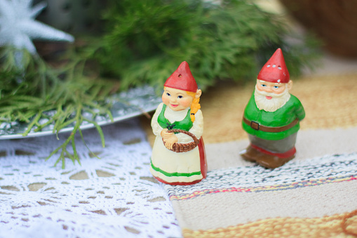 Two decorative ceramic figures of green gnomes stand on a table. Close up. Macro