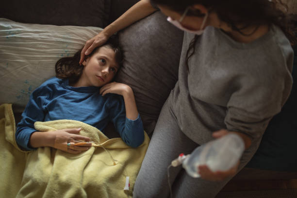 istock Boy lying sick on sofa and his mother taking care for him 1214530323