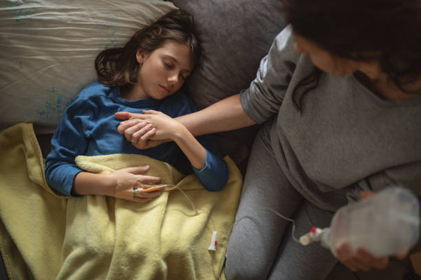istock Boy lying sick on sofa and his mother taking care for him 1214530358