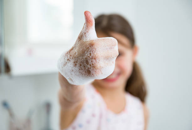 Little girl washing hands with water and soap in bathroom. Little girl washing hands with water and soap in bathroom. Kid showing thumbs up. Hands hygiene and virus infections prevention. ok sign photos stock pictures, royalty-free photos & images