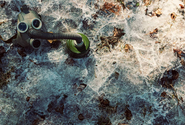 Vintage gas mask with filter lying on a layer of ice.