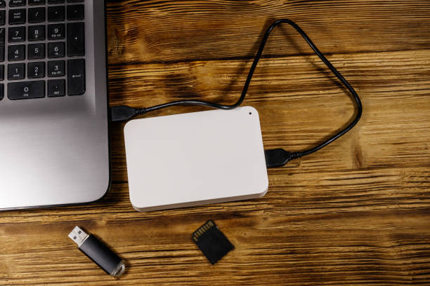 istock External HDD connected to laptop computer, SD memory card and USB flash drive on a wooden desk. Top view. Concept of data storage 1214534348