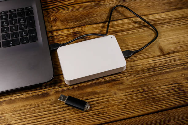 istock External HDD connected to laptop computer and USB flash drive on a wooden desk. Concept of data storage 1214534359