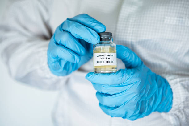 istock Scientific with protective suit holds vaccine coronavirus. Vaccination COVID-19 1214535175