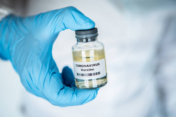 istock Scientific with protective suit holds vaccine coronavirus. Vaccination COVID-19 1214535254