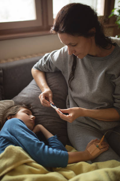 istock Boy lying sick on sofa and his mother taking care for him 1214535856