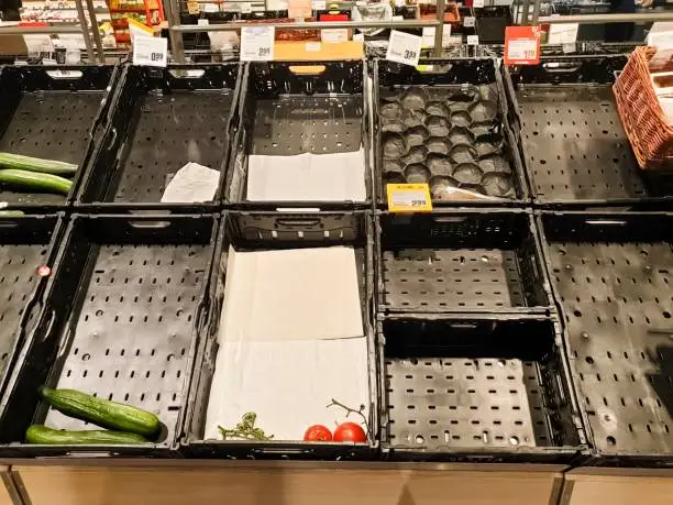 Empty vegetable crates and shelves caused by panic buying. Usually upcoming natural disasters cause people to stock up on food.
The reason for these empty crates and shelves are multifaceted purchases caused by the corona virus in march 2020.