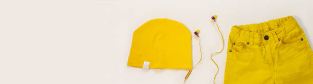 istock Yellow flatlay jeans, cotton hat and headphones on white background copy space,top view.Spring summer fashion clothing 1214537332