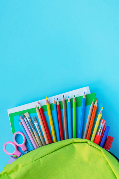 istock Green backpack with school supplies on blue background. 1214537721
