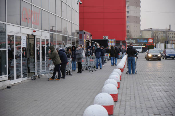 Shoppers stand in a queue outside a supermarket, after a Coronavirus lockdown is announced. Bucharest, Romania - March 24, 2020: Shoppers stand in a queue outside a supermarket, after a Coronavirus lockdown is announced. bucharest people stock pictures, royalty-free photos & images