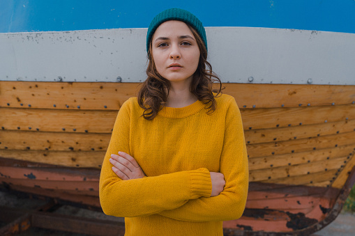 Portrait of young Caucasian woman in yellow sweater on the background of boat