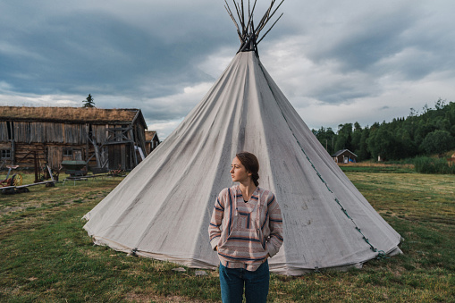 Young Caucasian woman standing near teepee