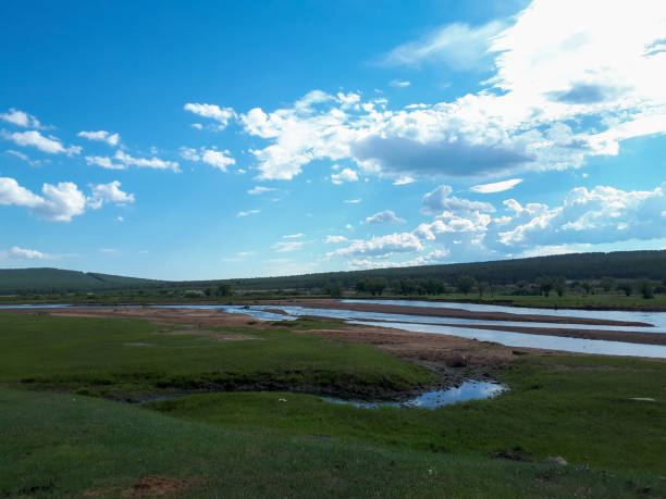 istock Photograph summer river green grass hills blue sky white clouds 1214539712