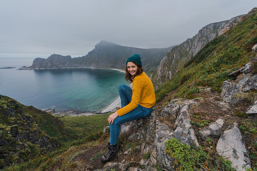 Young Caucasian woman  sitting with view on beach on Lofoten island