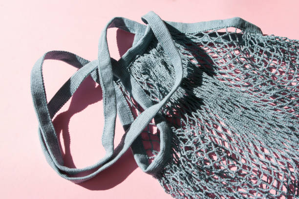 Blue cotton string knitted bag on pink background. Top view, flat lay. Zero waste, eco friendly shopping