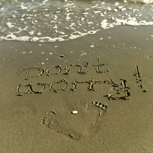 istock Words Don't Worry and footprints on beach sand 1214541733
