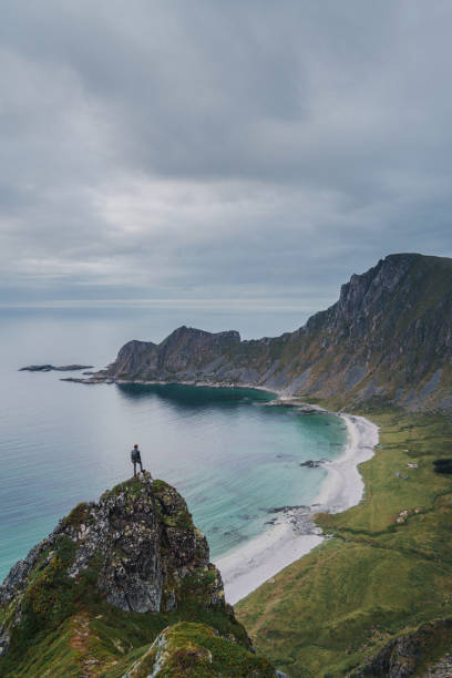 istock Man looking at Kvalvika beach while standing on rock 1214543525