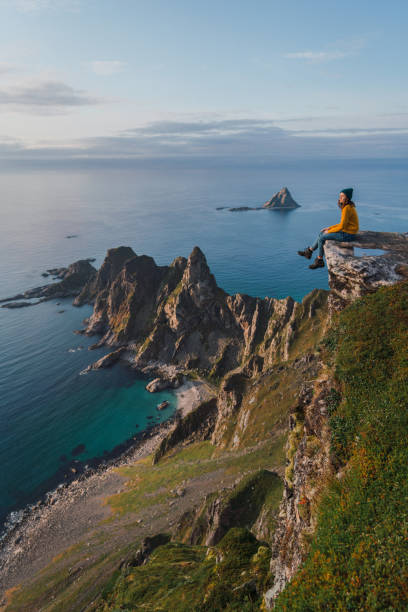 frau sitzt mit blick auf das meer auf lofoten insel - fjord stock-fotos und bilder