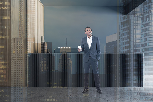 Cheerful African American businessman standing in stylish coffee shop interior with grey and wooden walls, concrete floor and bar counter with coffee machine. Toned image double exposure