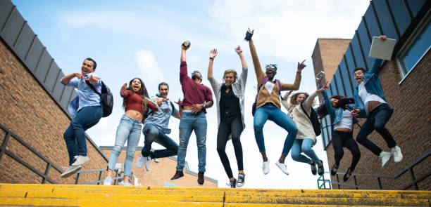 Group of Excited Students stock photo A multi-ethnic group of students jump in excitement at the top of the steps of their school. jumping teenager fun group of people stock pictures, royalty-free photos & images