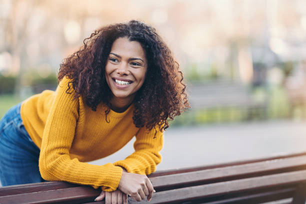 istock Cheerful young woman resting by a bench in a park 1214546881
