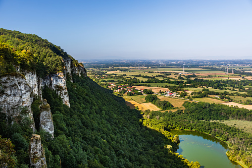 Aerial high angle view of beautiful cliffs early in the morning, on the border between the department of Ain, with plain land and meadows, and Isere on left in summer from the archaeological site of Larina. Taken in France, in Auvergne-Rhone-Alpes, in Europe.