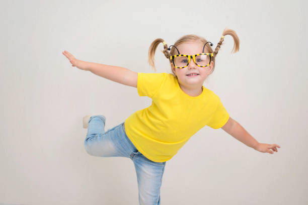 Happy funny little girl in party bee eyeglasses with funny pigtails braids in yellow t-shirt and jeans. Happy funny little girl in party bee eyeglasses with funny pigtails braids in yellow t-shirt and jeans. bee costume stock pictures, royalty-free photos & images