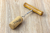 A basic corkscrew with a cork on a wooden table. Tokaji is wine's name written on cork from Tokaj wine region, Hungary.