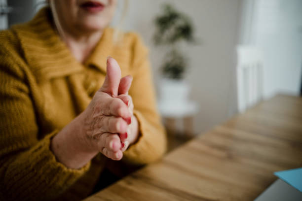 istock An older woman disinfects her hands 1214553195