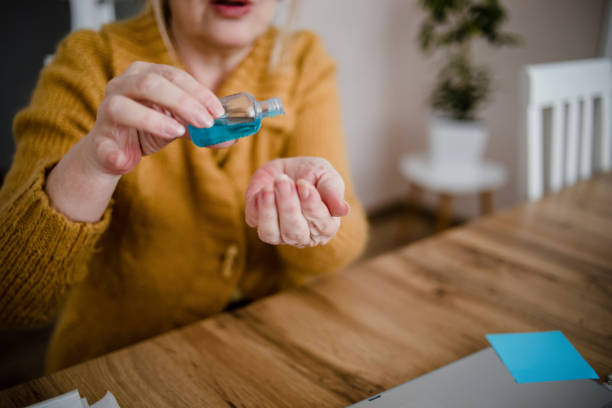 istock An older woman disinfects her hands 1214553927