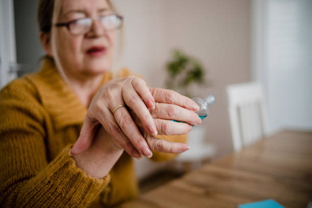 istock An older woman disinfects her hands 1214555179