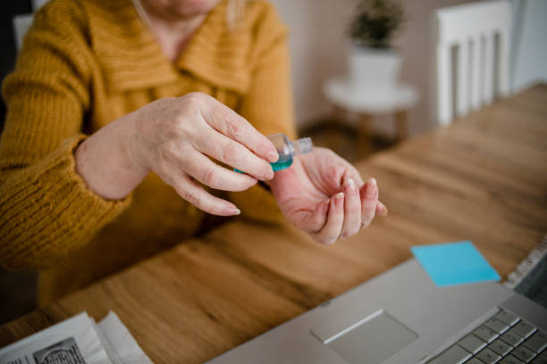 istock An older woman disinfects her hands 1214557278