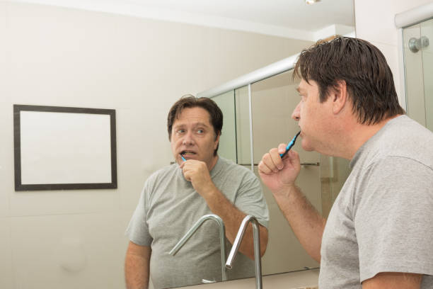 istock Older man in the bathroom brushing his teeth 1214557364