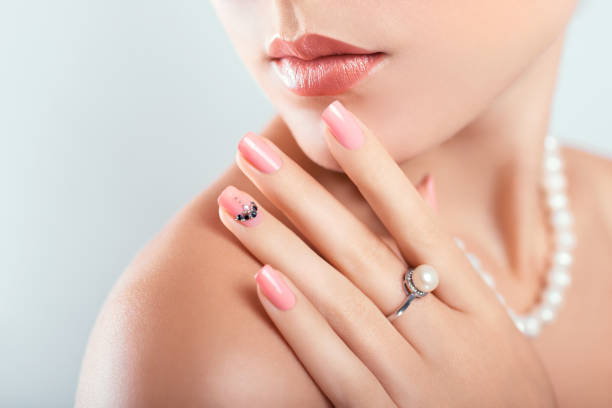 nagelkunst und design. schöne frau trägt make-up und perlenschmuck zeigt rosa maniküre mit edelsteinen - pearl jewelry necklace women stock-fotos und bilder