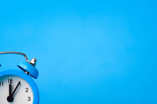 istock Alarm clock in the lower left corner on a blue background 1214558227