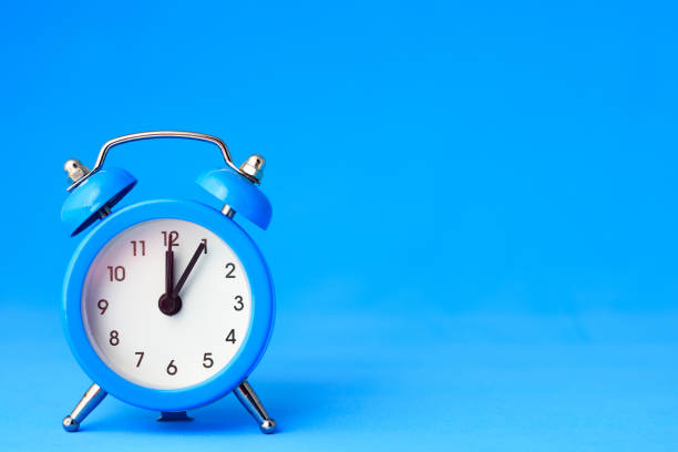 istock Alarm clock on a blue background, on the right is an empty place 1214558228