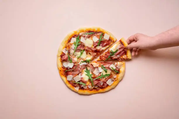 Photo of Pizza ham and cheese on pink background. Taking pizza slice