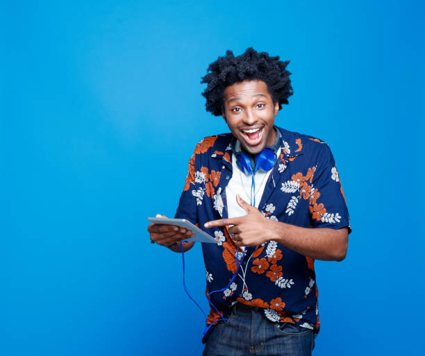 jeune homme excité dans la chemise hawaïenne retenant la tablette numérique - floral pattern audio photos et images de collection
