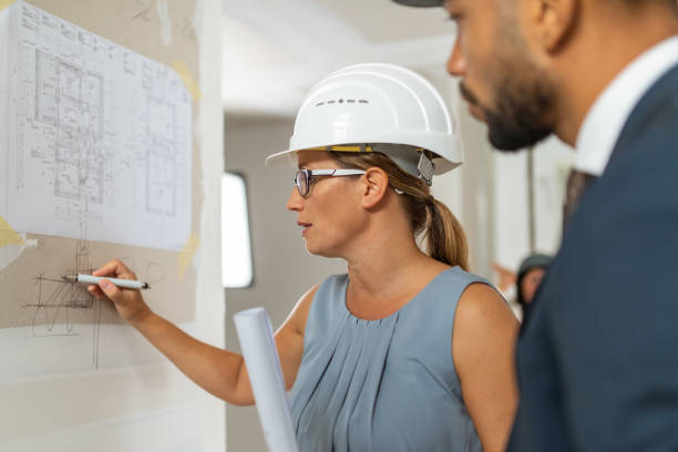 istock Female architect explaining blueprint details to house owner 1214560510