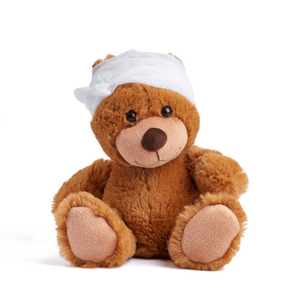 teddy bear with a bandaged head in a white medical bandage on a white background brown teddy bear with a bandaged head in a white medical bandage on a white background, concept of child trauma, headache behavior teddy bear doll old stock pictures, royalty-free photos & images