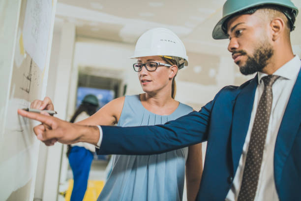 istock Female architect explaining blueprint details to house owner 1214561181